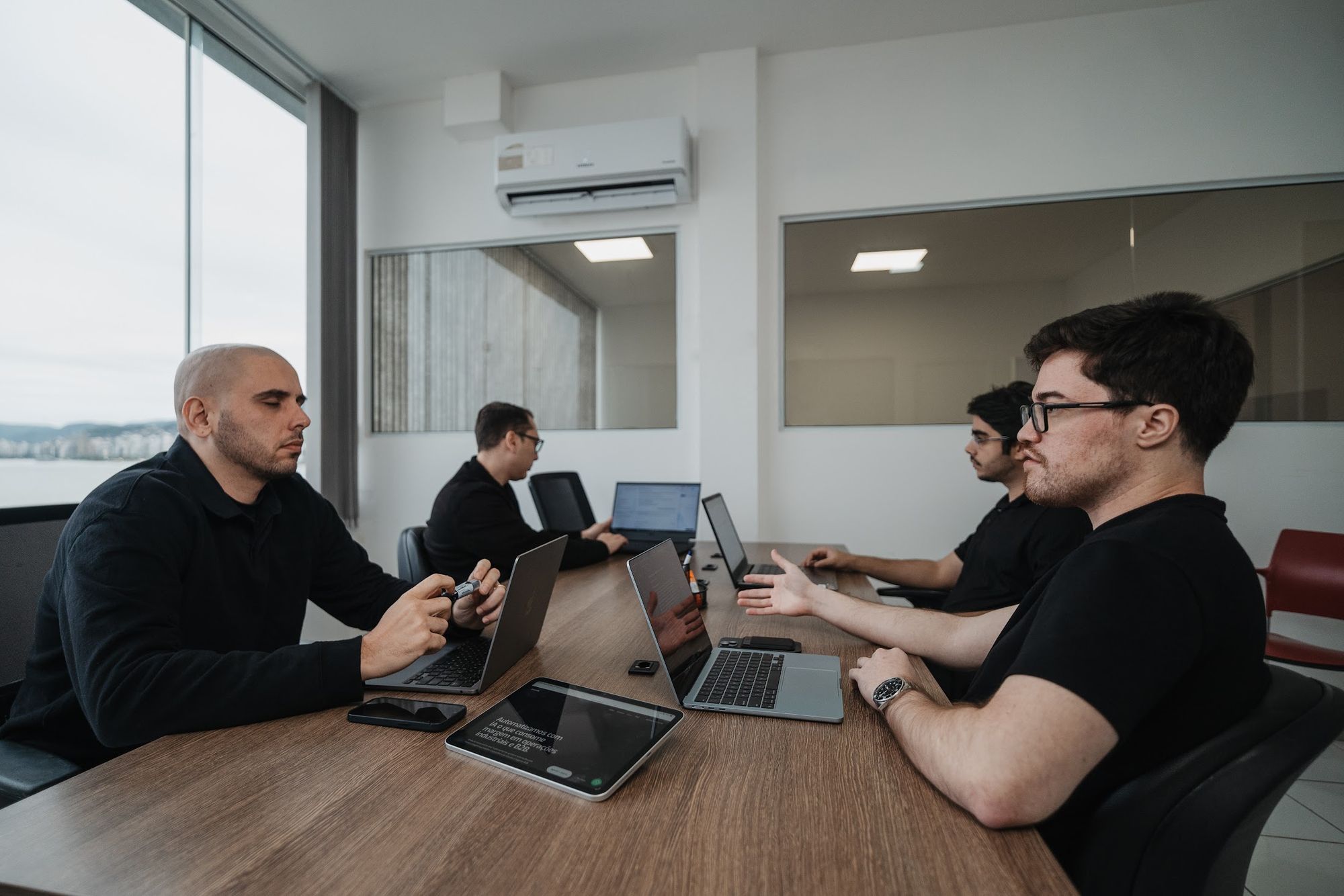 Time da Artemis em reunião na sala do escritório, com a baía ao fundo